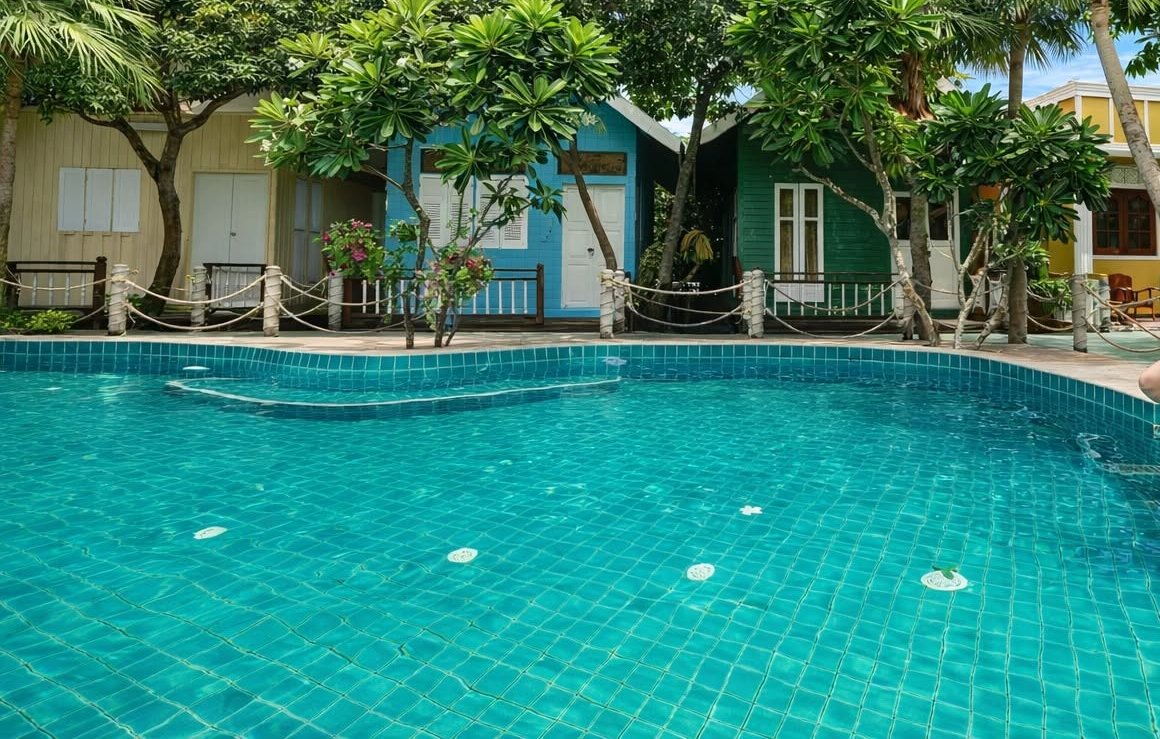 สระว่ายน้ำท่ามกลางสวนต้นไม้และบังกะโล